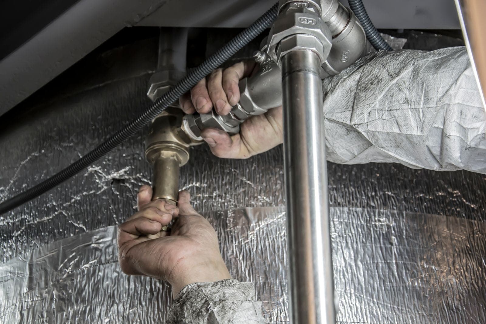 A plumber's hands tightening pipe fittings