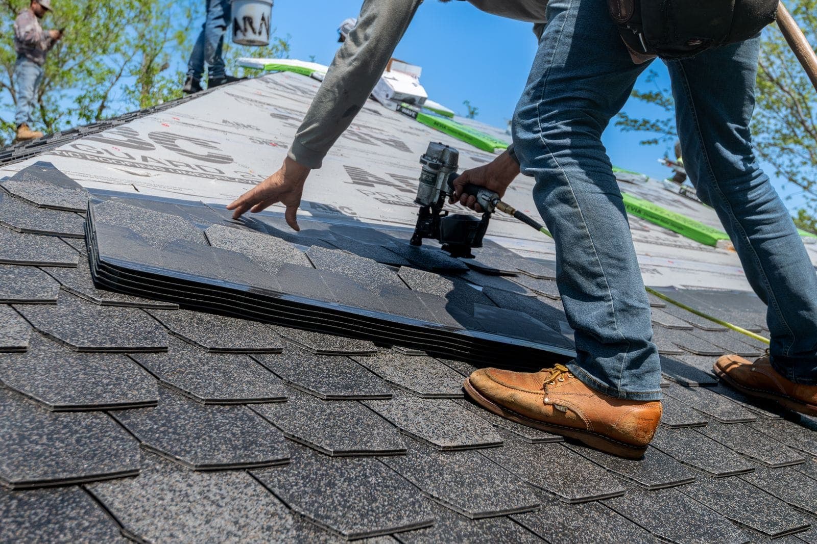 A roofer installing asphalt shingles on a home