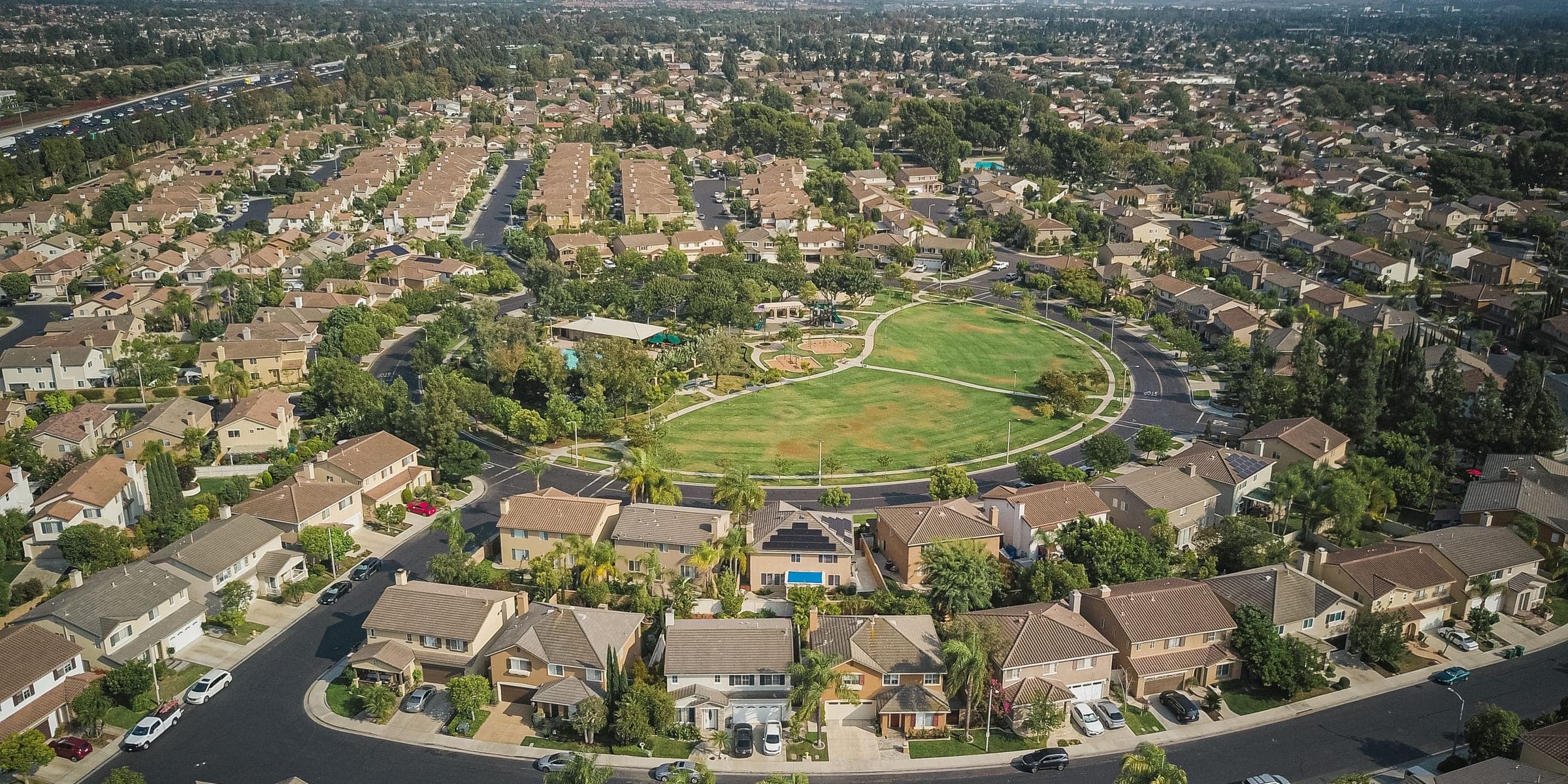 Aerial view of a suburban neighborhood with tile roofs around a green park