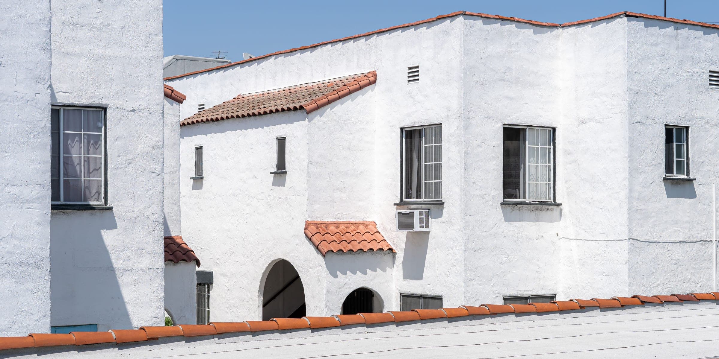 White stucco Spanish style homes with terracotta roof tiles under a clear blue sky
