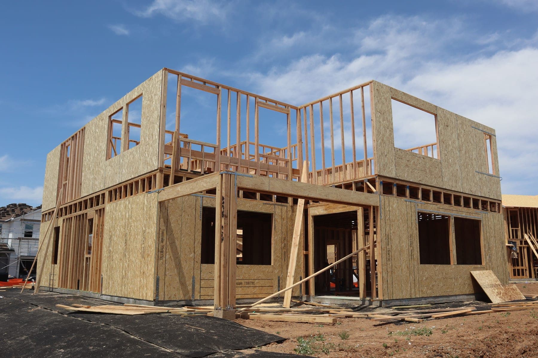 Wood-framed house with plywood sheathing under construction on a sunny day