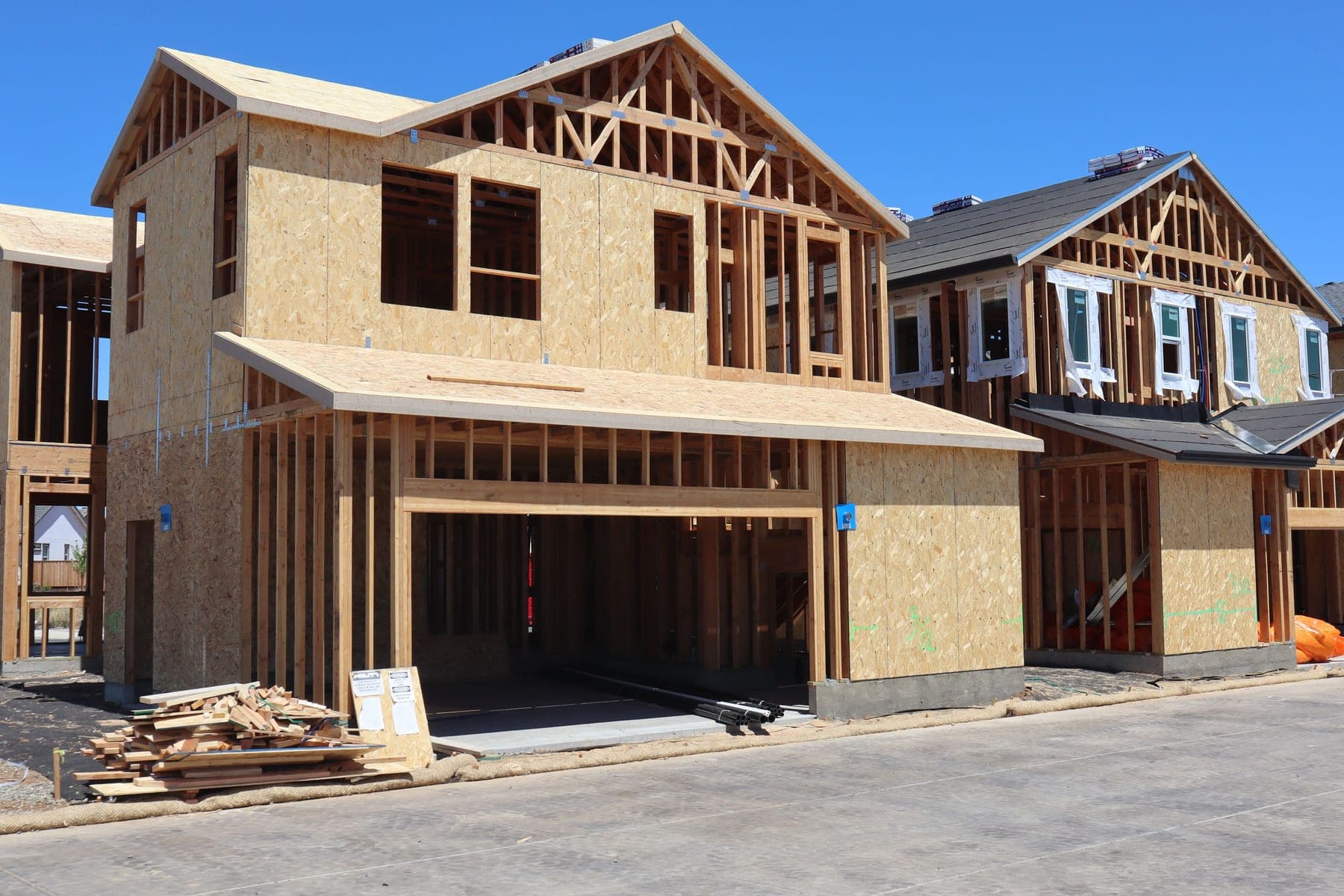Wood-framed two-story houses under construction on a new residential street