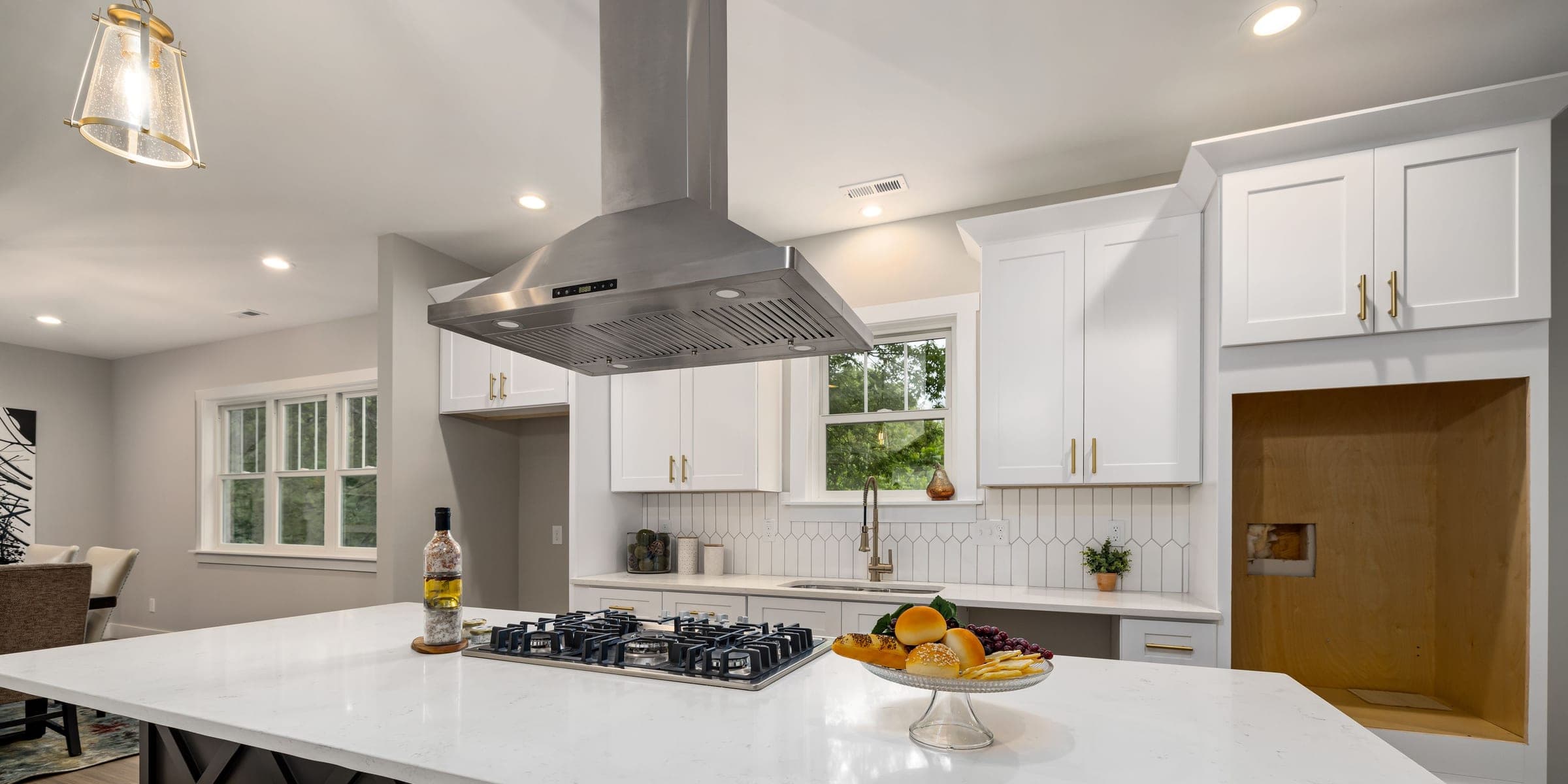 Stainless steel range hood above a gas cooktop on a white kitchen island